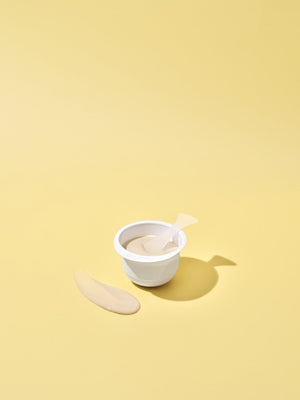 White container filled with beige cream and a small spatula on a yellow background, showcasing the 3X Boosting Modeling Mask - Vitamin | Leaders skincare product.