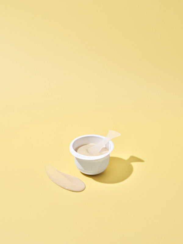 White container filled with beige cream and a small spatula on a yellow background, showcasing the 3X Boosting Modeling Mask - Vitamin | Leaders skincare product.