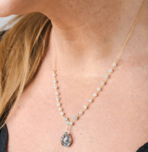 Close-up of a woman wearing the Alice Rosary Necklace | Liv & B featuring delicate light-colored beads and a teardrop-shaped pendant on a fine gold chain.