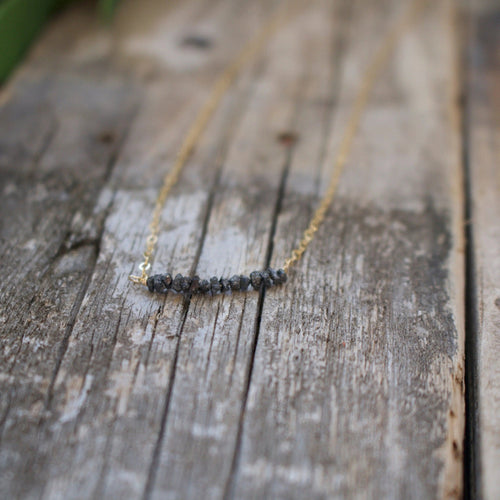 Delicate gold chain necklace featuring a row of raw black diamonds, showcasing natural beauty and elegance in the Diamonds In The Raw Sterling Silver Necklace | Liv & B.