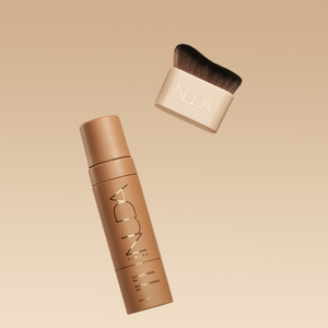 Blending Brush | NUDA with soft, dense bristles and a beige handle paired with a sleek NUDA branded bottle, both designed for flawless skincare and makeup application.