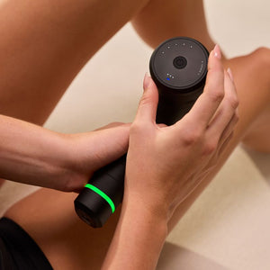 Person holding a black Hypervolt 3 | Hyperice massage device with LED indicators glowing while applying it to forearm for muscle recovery and relaxation.