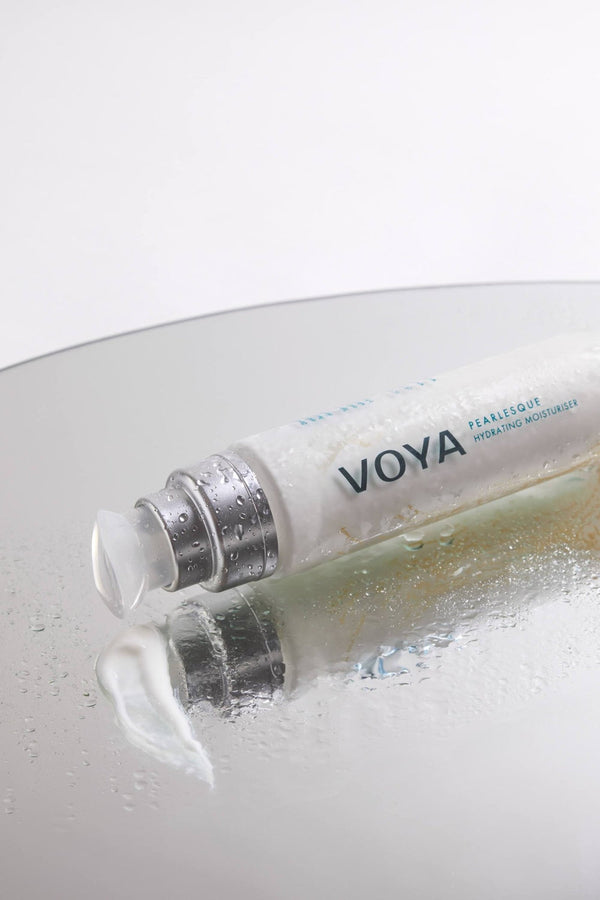 Pearlesque Hydrating Moisturiser | VOYA tube with cream on reflective surface, showcasing hydrating skincare for moisturizing and nourishing body care routines.