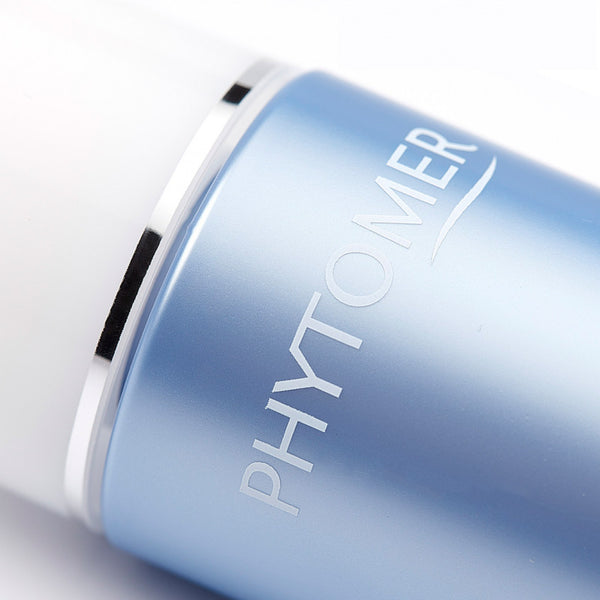 Close-up of a blue bottle with silver accents labeled Perfect Visage Gentle Cleansing Milk | Phytomer, highlighting a skincare product in a sleek design.