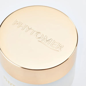 Close-up of a luxury skincare jar lid embossed with PHYTOMER branding, part of the Perles Des Mers Longevity Cream | Phytomer packaging, reflecting a smooth gold finish.