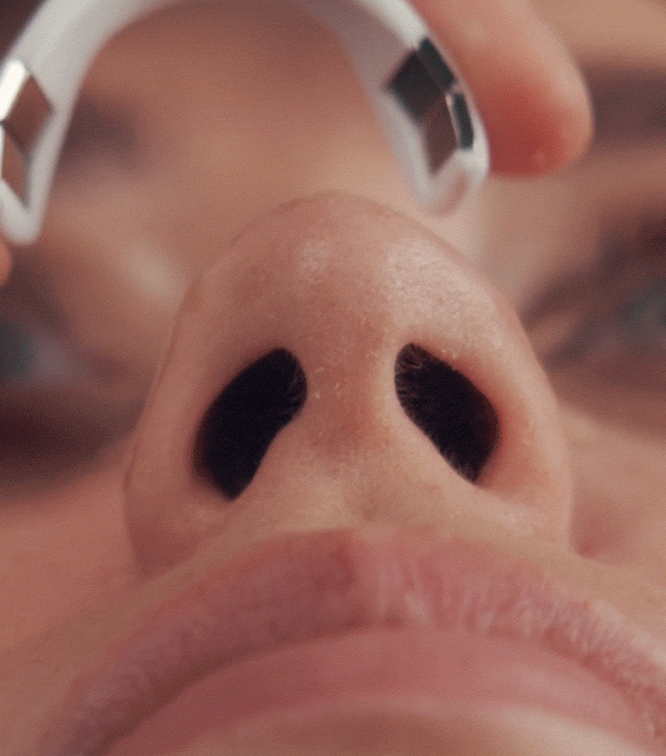Close-up of a person applying an Intake Nasal Strip Starter Kit - 15 Pack | Intake Breathing strip to the bridge of their nose to aid in breathing and nasal airflow.