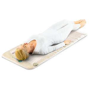 Woman in white activewear relaxing on a beige SOFT-Mat™ Full Short 6024 InfraMat Pro® | HealthyLine wellness device designed for body care and recovery.