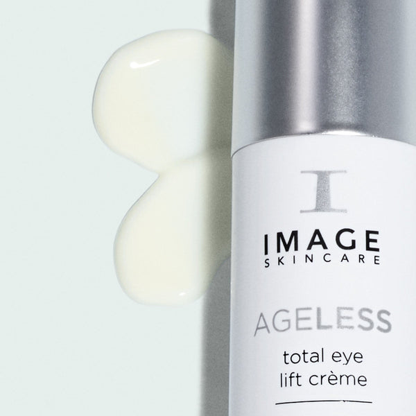 Close-up of a bottle of AGELESS total eye lift crème | IMAGE Skincare with a smooth cream texture swatched beside it, highlighting skincare and body care product quality.