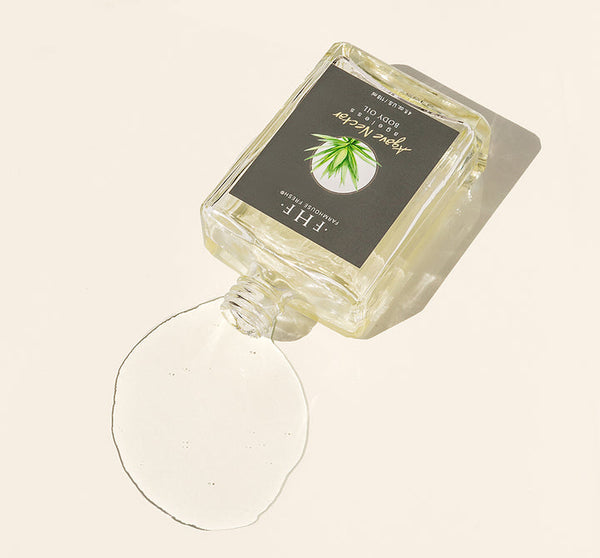 Agave Nectar Ageless Body Oil | Farmhouse Fresh bottle tilted with clear oil spilling on a light surface, showcasing a fresh natural skincare product for body care and wellness.
