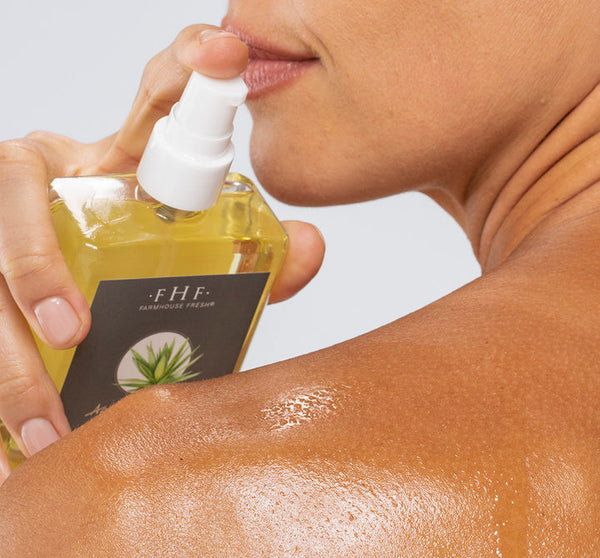 Woman spraying Agave Nectar Ageless Body Oil | Farmhouse Fresh on her shoulder, showcasing glistening, moisturized skin in a close-up skincare moment.
