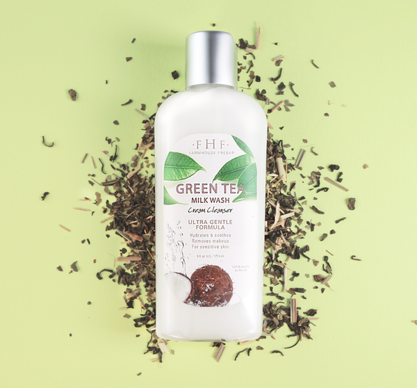 Bottle of Green Tea Milk Wash | Farmhouse Fresh cream cleanser displayed on green tea leaves against a light green background, highlighting skincare and gentle cleansing benefits.