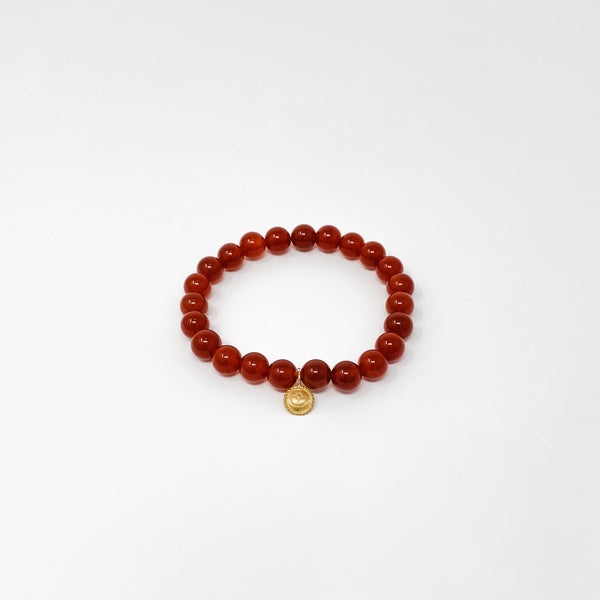Assorted Satya Bracelets | Satya featuring polished red beads with a small golden charm on a clean white background, reflecting wellness and mindful accessory style.