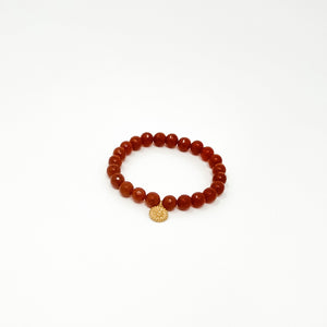 A single beaded bracelet with deep reddish-brown stones and a small gold charm, showcasing elegant, natural craftsmanship in the Assorted Satya Bracelets | Satya collection.