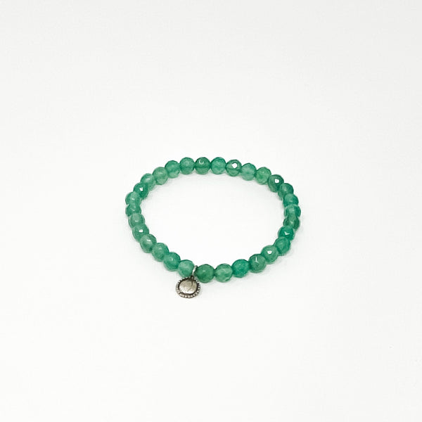 Close-up of a green beaded bracelet with a small silver charm, part of the Assorted Satya Bracelets | Satya collection, styled for wellness and mindful living.