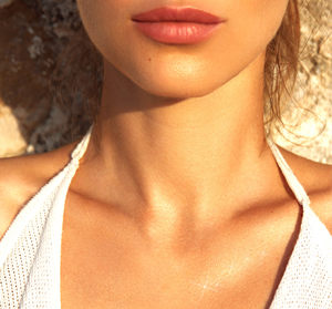 Close-up of a woman’s glowing neck and chest area, highlighting radiant skin with a subtle shimmer from Lustre Drench® Instant Glow Dry Oil | Farmhouse Fresh.