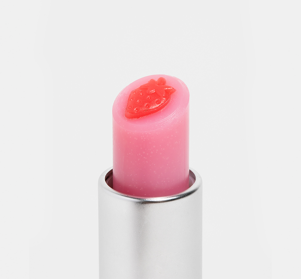Close-up of a pink lip balm stick featuring a red strawberry-shaped detail on top, part of the Strawberry Mood Fruit™ Lip Therapy | Farmhouse Fresh skincare product line.