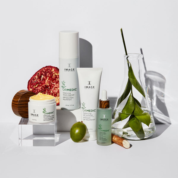 Collection of IMAGE Skincare products featuring ORMEDIC balancing gel polisher | IMAGE Skincare alongside natural ingredients like pomegranate and green leaves, emphasizing skincare and wellness.