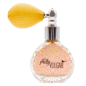 Vintage-style clear glass bottle with pink glitter powder and a yellow bulb atomizer spray labeled Glitter Dust | Pretty Vulgar for beauty use.