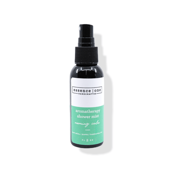 A black spray bottle of Aromatherapy Shower Mist | Essence One with a green and white label, designed for a calming wellness and body care experience.