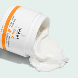 Opened jar of VITAL C hydrating repair crème | IMAGE Skincare showing thick, creamy white moisturizing skincare product spilling out on a light background.