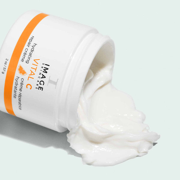 Opened jar of VITAL C hydrating repair crème | IMAGE Skincare showing thick, creamy white moisturizing skincare product spilling out on a light background.
