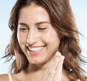 Smiling woman with glowing, hydrated skin applying Radiance Maker 3-step Instant Spa Facial | Farmhouse Fresh skincare treatment for a fresh, radiant complexion.