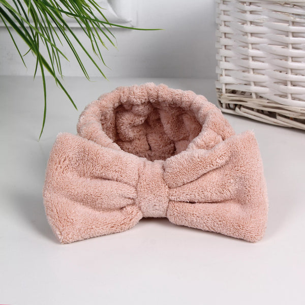 Soft pink plush headband with a large bow detail, designed for comfortable wear during skincare or spa routines, Luxe Spa Headbands | Lucky Owl.