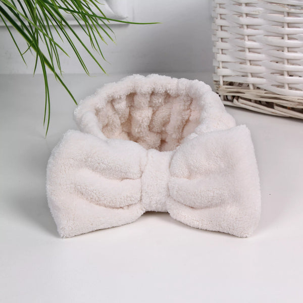 Soft, white textured headband with a large bow detail, designed for skincare and wellness routines, shown in a calm spa setting, Luxe Spa Headbands | Lucky Owl.